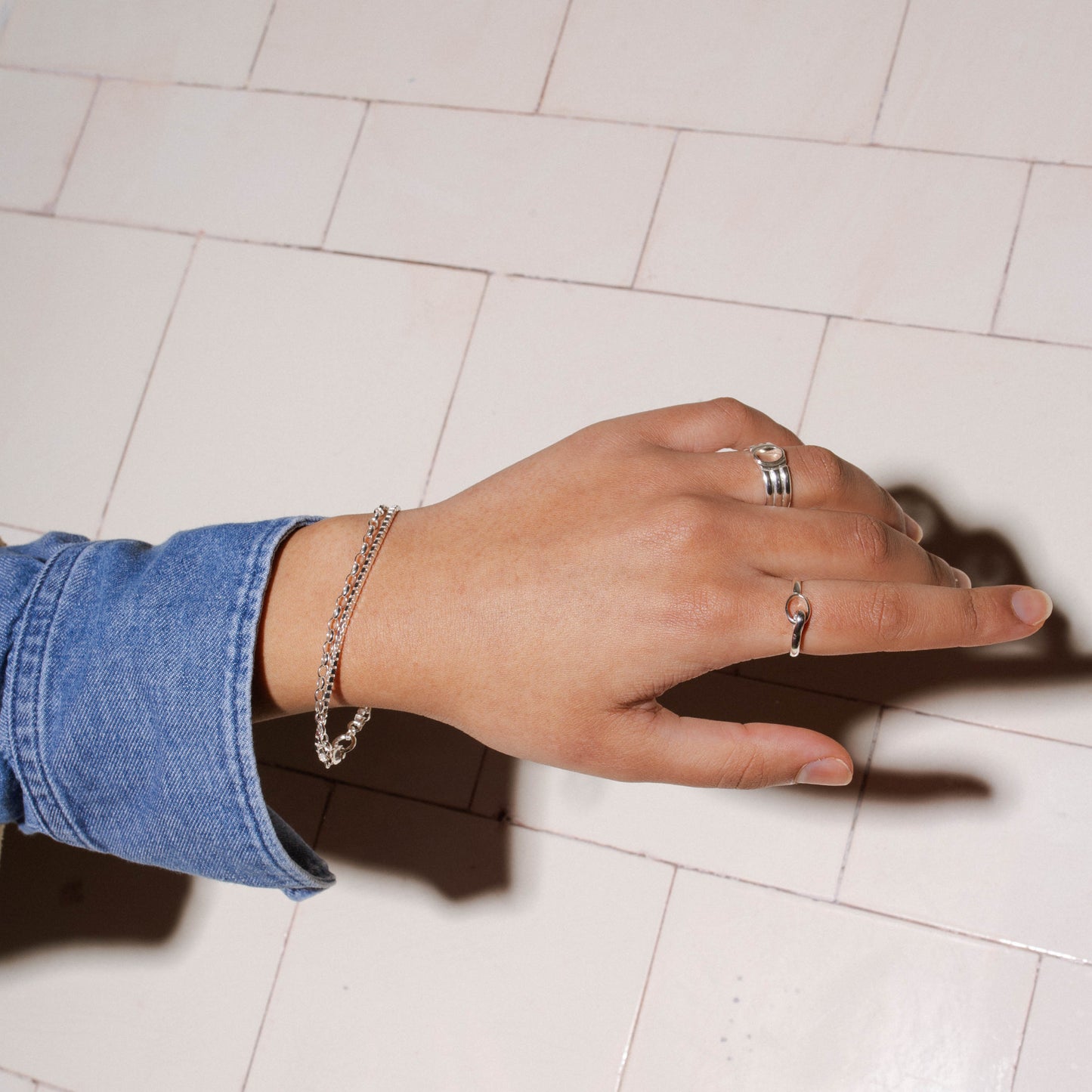 Duo Venetian Bracelet in sterling silver worn by a model alongside the Loop Ring and Outline Signet Ring in sterling silver
